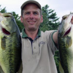 An Aquatic Environment Consultant employee holds two large mouth bass
